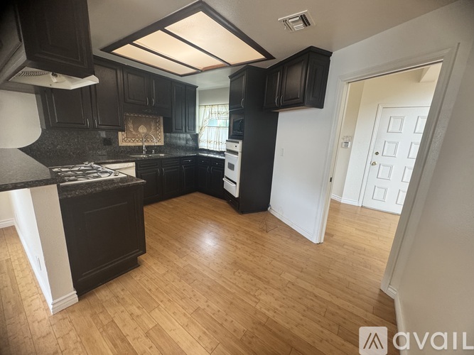 A kitchen with black cabinets and a white stove top oven.