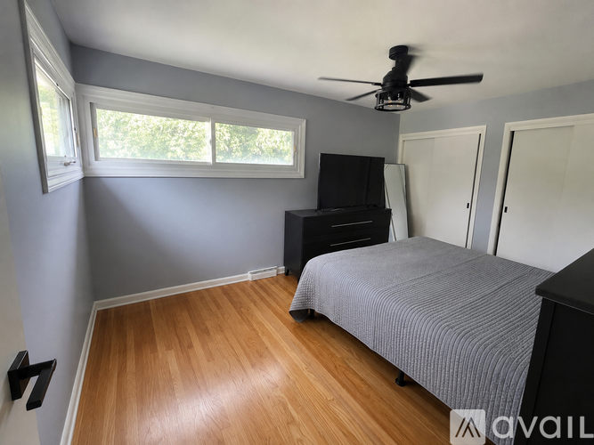 A bedroom with a bed, dresser, and ceiling fan.