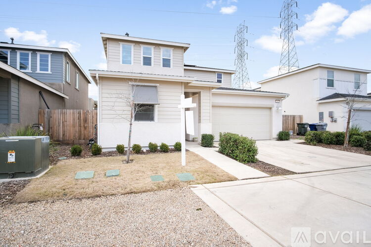 A white house with a brown fence and a green bush in front.