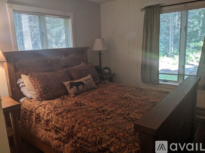 A bedroom with a bed, nightstand, and window.