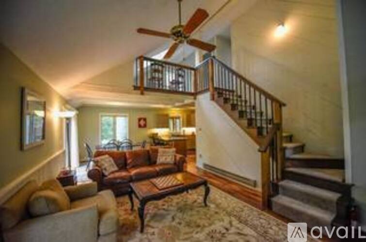 A living room with a staircase and a ceiling fan.