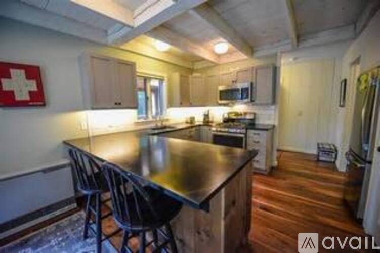 A kitchen with a black countertop and wooden flooring.
