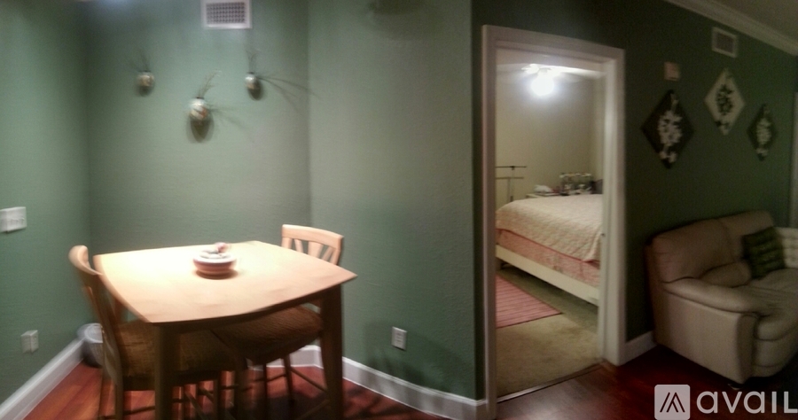 A dining table with chairs and a bedroom with a bed and a chair are visible.