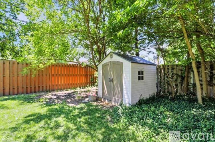A small white shed sits in a lush green garden.