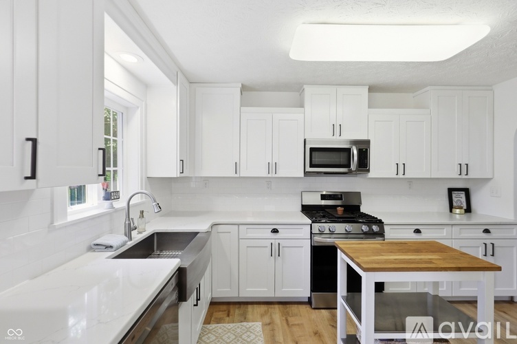 A kitchen with white cabinets and a wooden table.