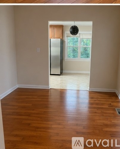 A room with wooden floors and a doorway leading to another room.
