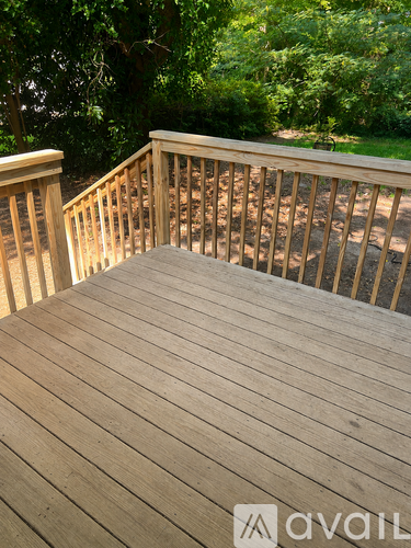 A wooden deck with a railing and steps leading to a grassy area.