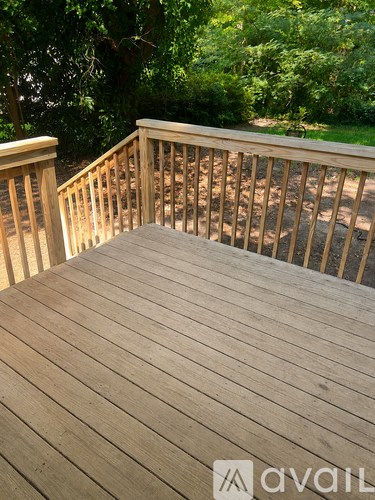 A wooden deck with a railing and steps leading to a grassy area.