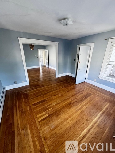 A room with wooden flooring and white walls.