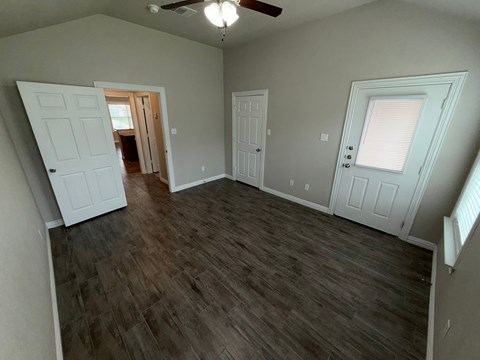 A room with a ceiling fan and two doors.