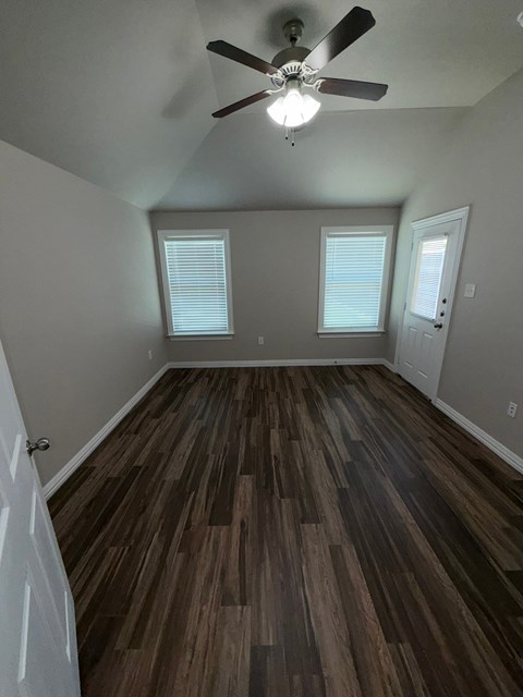 A room with a ceiling fan and wood flooring.