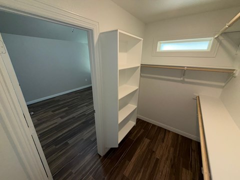 A small room with a window and a wooden floor.