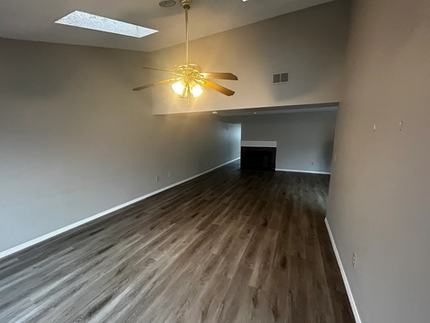 A room with a ceiling fan and wooden flooring.