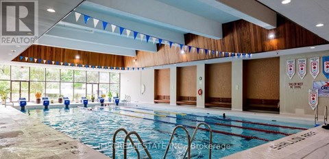 A large indoor swimming pool with a REALTOR sign in the corner.
