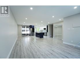 A spacious room with wooden flooring and a large window with curtains.