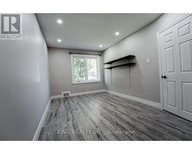 A room with wooden flooring and a window with a view of trees.