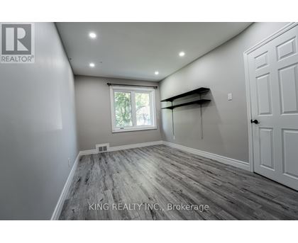 A room with wooden flooring and a window with a view of trees.