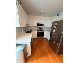 A kitchen with white cabinets and a stainless steel refrigerator.