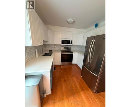 A kitchen with white cabinets and a stainless steel refrigerator.
