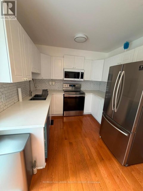 A kitchen with white cabinets and a stainless steel refrigerator.