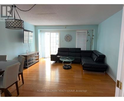 A living room with a black couch and a glass coffee table.