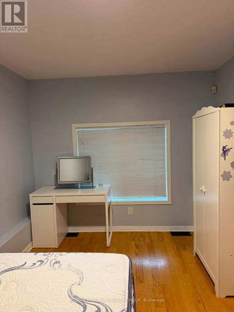 A bedroom with a bed, desk, and a refrigerator.