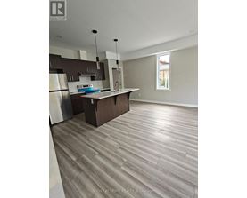 A modern kitchen with wooden flooring and stainless steel appliances.