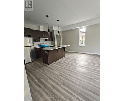 A modern kitchen with wooden flooring and stainless steel appliances.