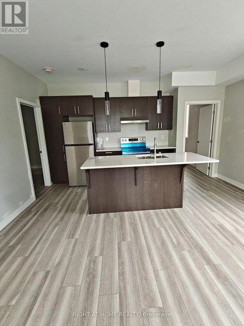 A modern kitchen with a central island and dark brown cabinets.