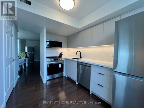 A kitchen with white cabinets and a stainless steel refrigerator.