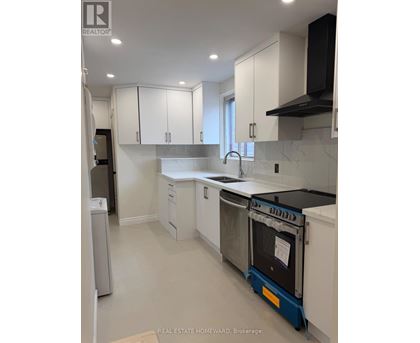 A kitchen with white cabinets and a black range hood.