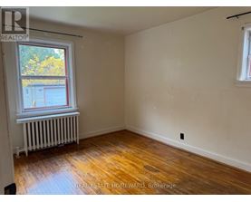 A room with wooden floors and a window with a view of a building outside.