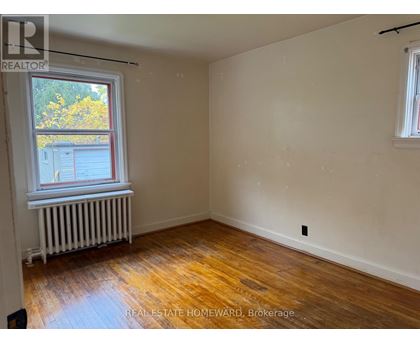 A room with wooden floors and a window with a view of a building outside.
