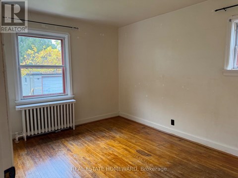 A room with wooden floors and a window with a view of a building outside.
