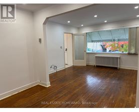 A room with wooden floors and white walls, with a door leading to a balcony.