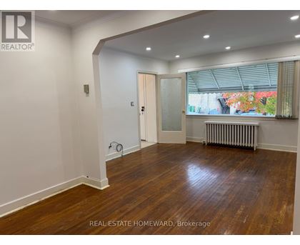 A room with wooden floors and white walls, with a door leading to a balcony.