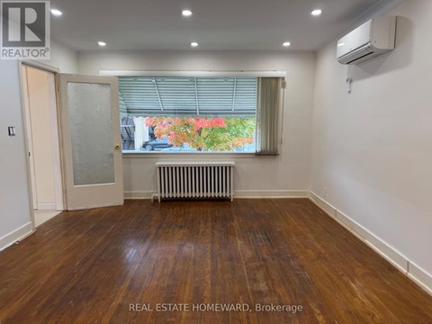 A room with wooden floors and a window with blinds.