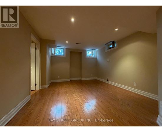 A spacious room with wooden flooring and two windows.
