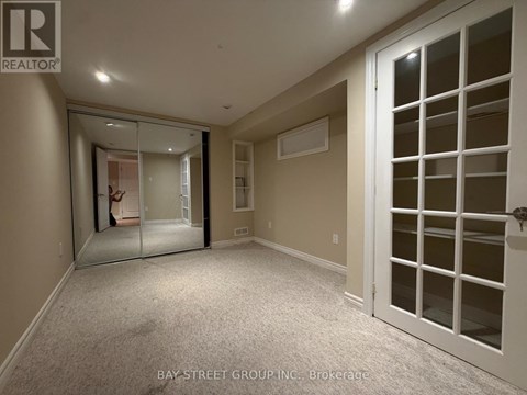 A spacious room with a white door and a mirror on the wall.