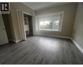 A room with a grey floor and a window with blinds.