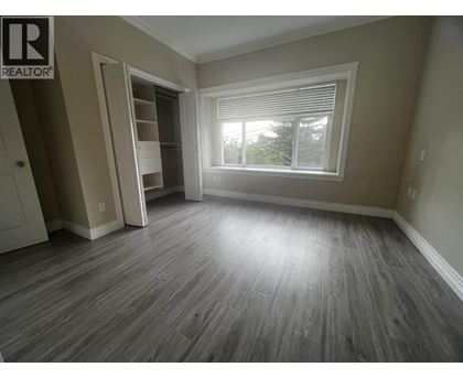 A room with a grey floor and a window with blinds.