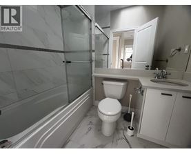 A white toilet sits in a bathroom with a marble floor and a glass shower.