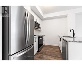 A kitchen with a stainless steel refrigerator and a microwave above the oven.