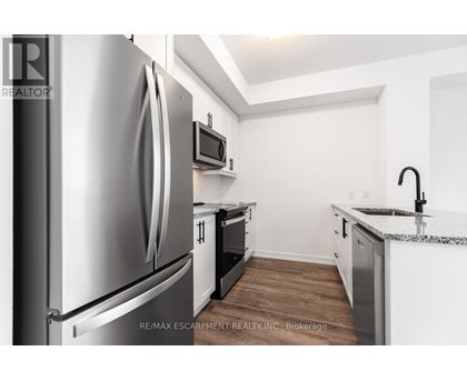 A kitchen with a stainless steel refrigerator and a microwave above the oven.