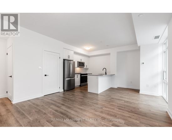 A spacious kitchen with white cabinets and a wooden floor.