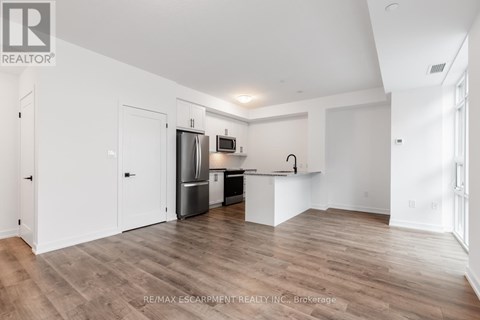 A spacious kitchen with white cabinets and a wooden floor.