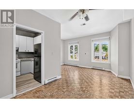 A spacious room with a kitchen area and a ceiling fan.
