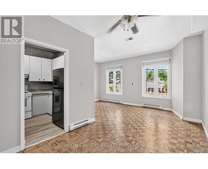 A spacious room with a kitchen area and a ceiling fan.