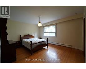 A bedroom with a bed, nightstand, and window.