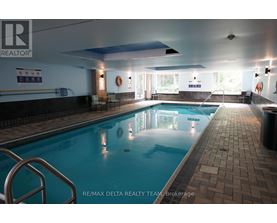 A large indoor swimming pool with a REALTOR® sign on the wall.